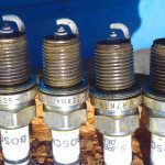 What does carbon deposits on spark plugs and its color indicate?